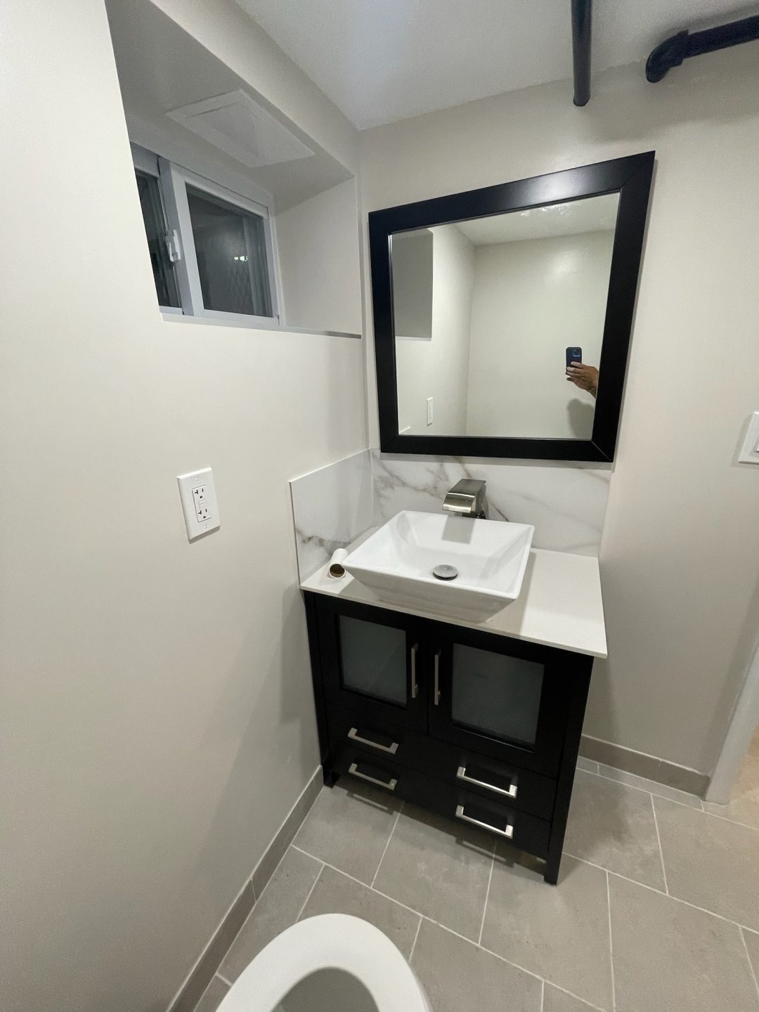Modern bathroom vanity with a square sink, large mirror, and tiled floor, seen from above.