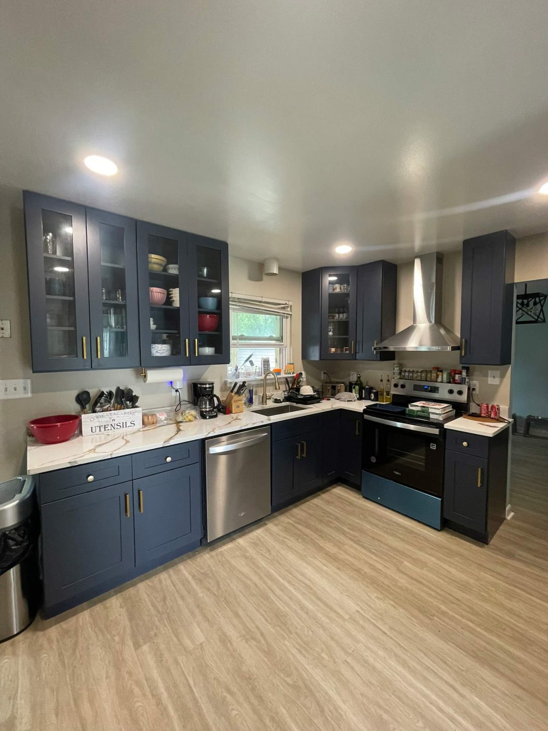 Modern kitchen with blue cabinets, stainless steel appliances, and light wood flooring.