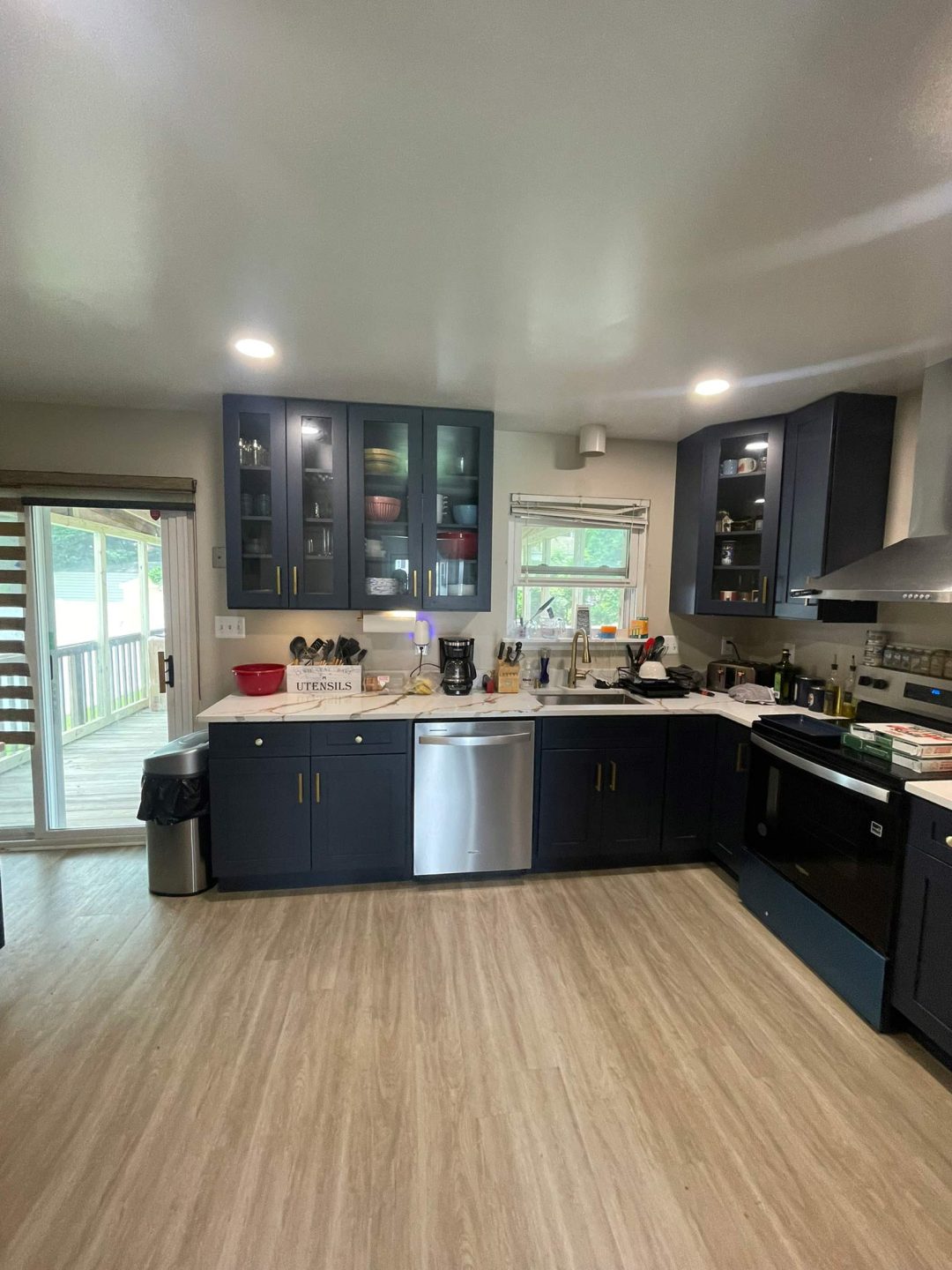Modern kitchen with navy cabinets, stainless steel appliances, and large windows letting in natural light.