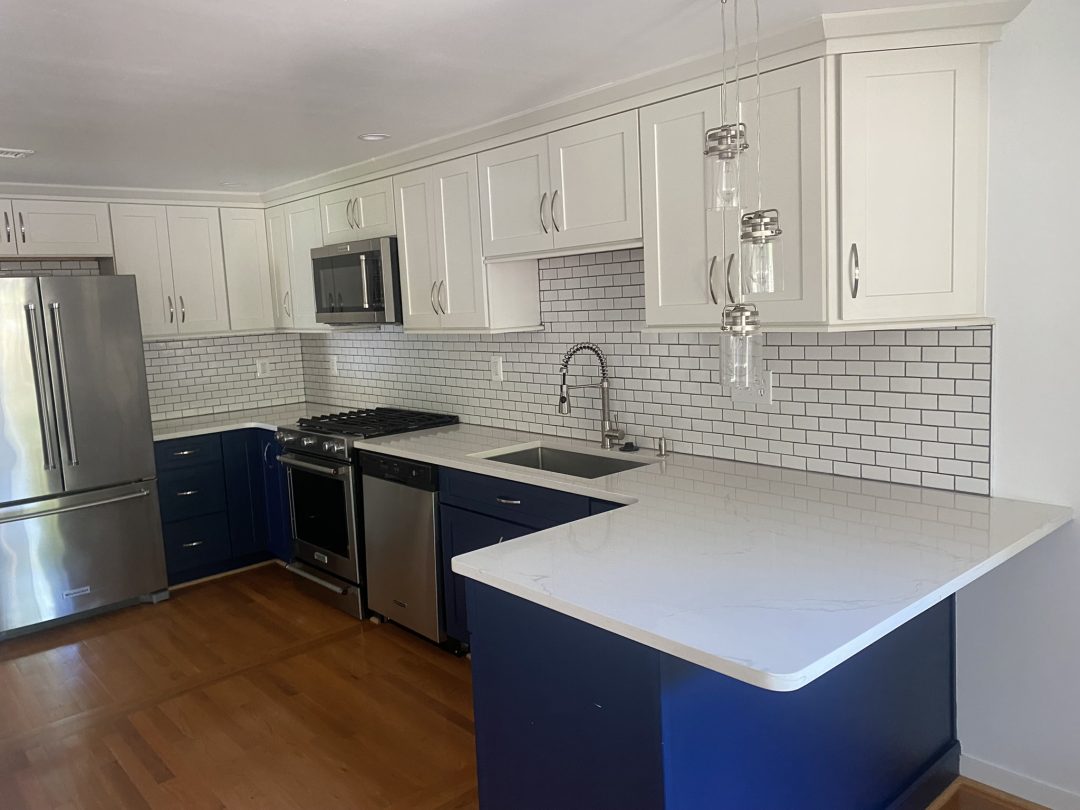 Modern kitchen with white cabinets, subway tile backsplash, stainless steel appliances, and wood floors.
